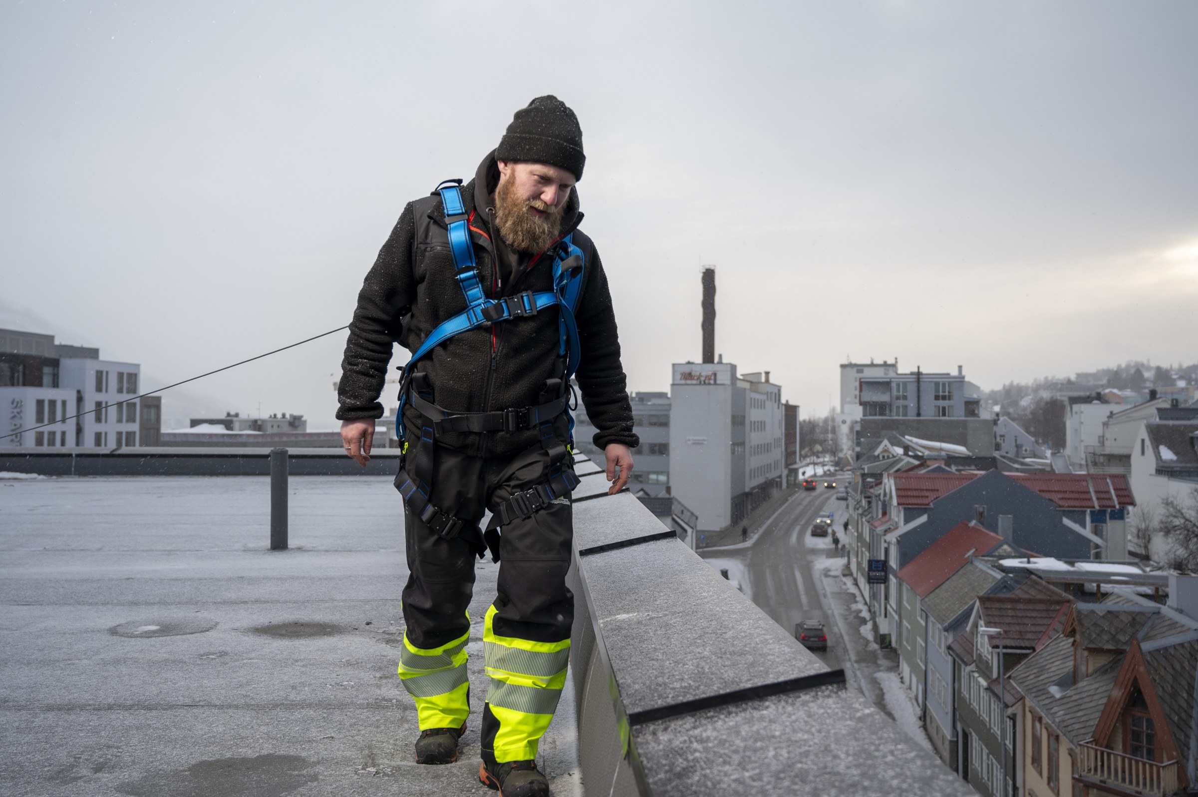 Medarbeider med fallsikringsutstyr på et tak i Tromsø