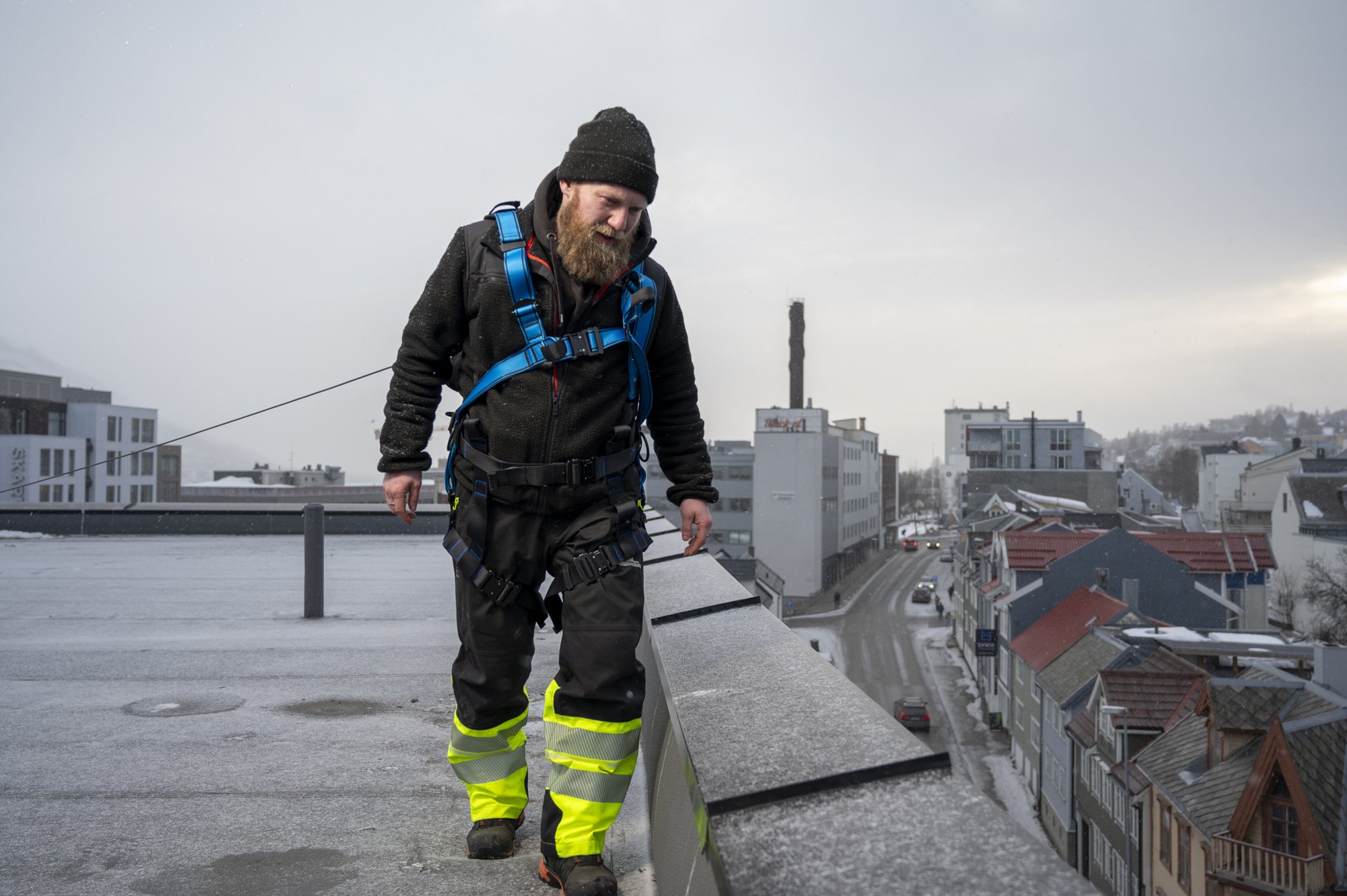 Medarbeider på et tak med utsikt over bygninger i Tromsø