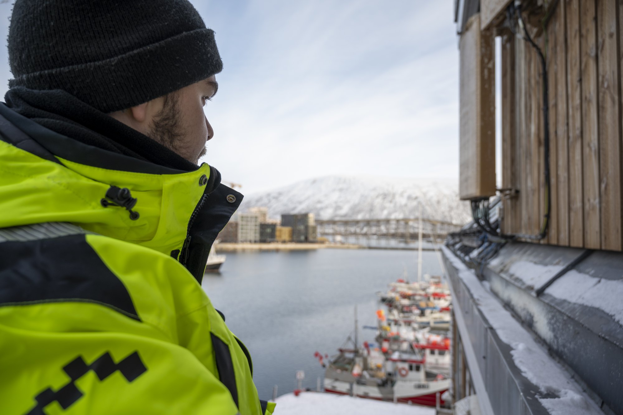 Medarbeider ved en utvendig fasade med utsikt over Tromsø